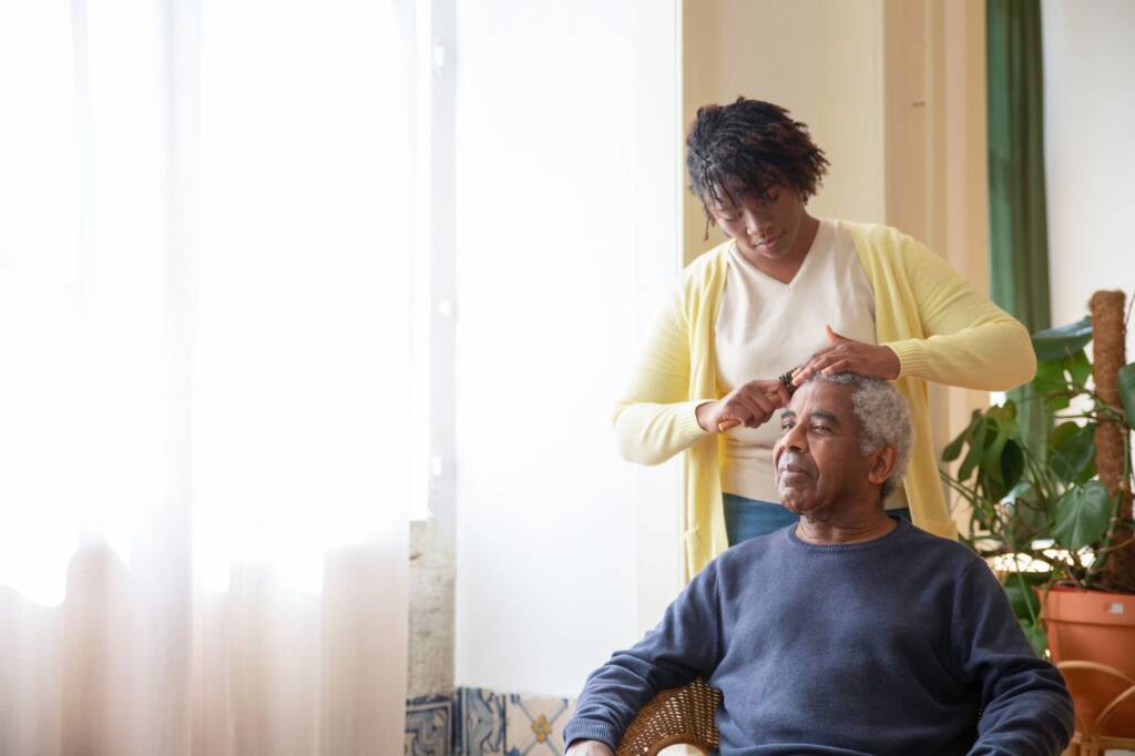 A carer combing an older man's hair at home