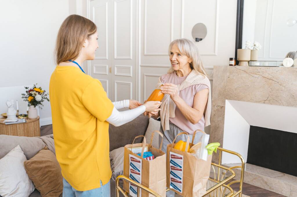 A carer bringing in shopping for an older woman at home