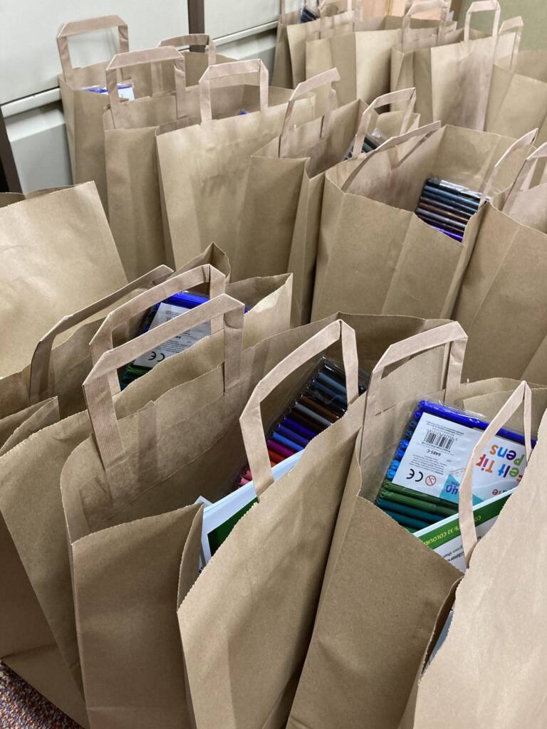 Paper bags packed with felt-tip pens and craft supplies, ready to hand out