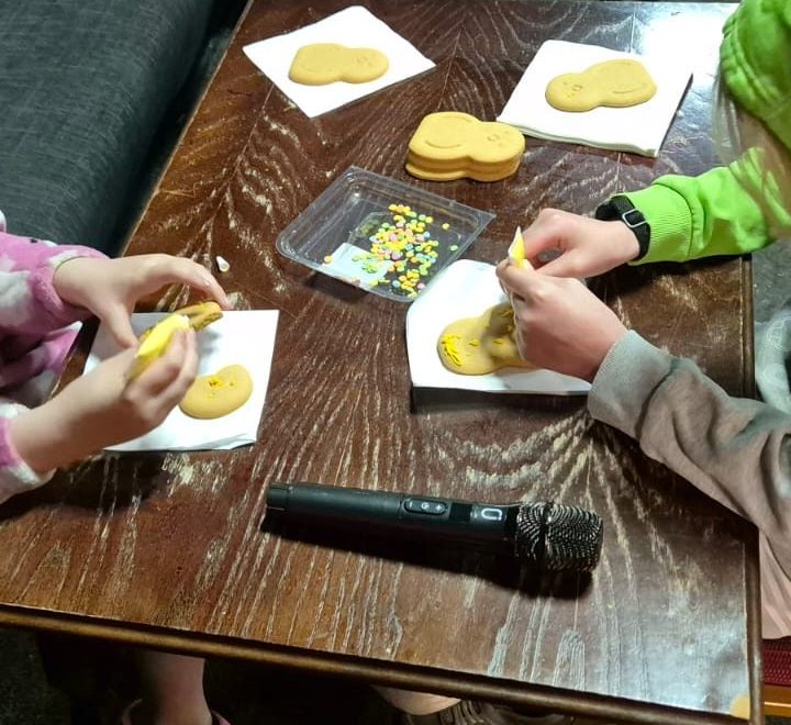 Hands decorating biscuits with icing and sprinkles