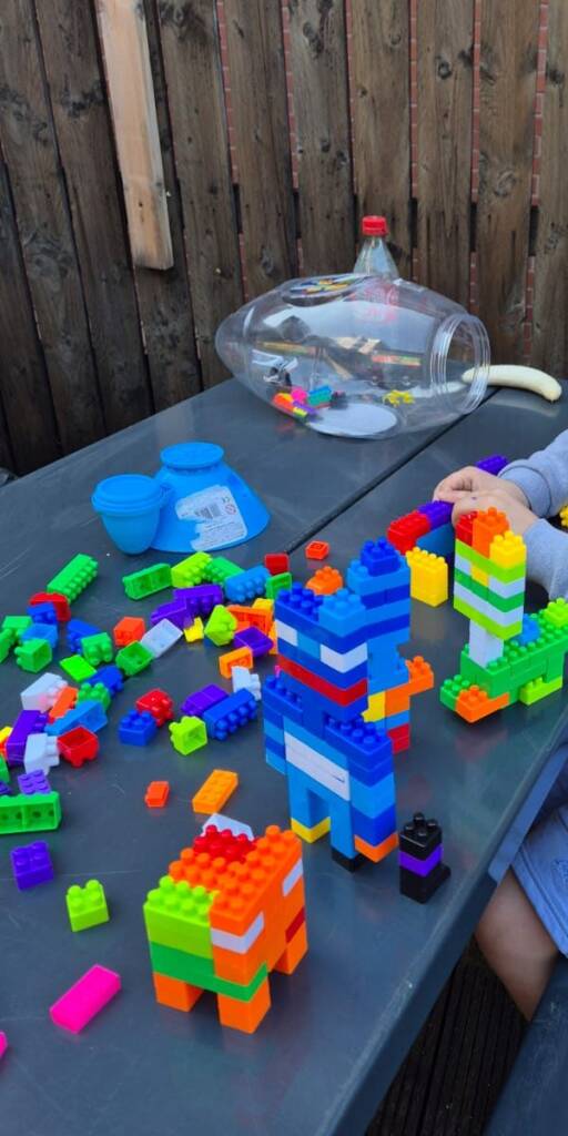 A tall tower and models built from plastic bricks on an outdoor table