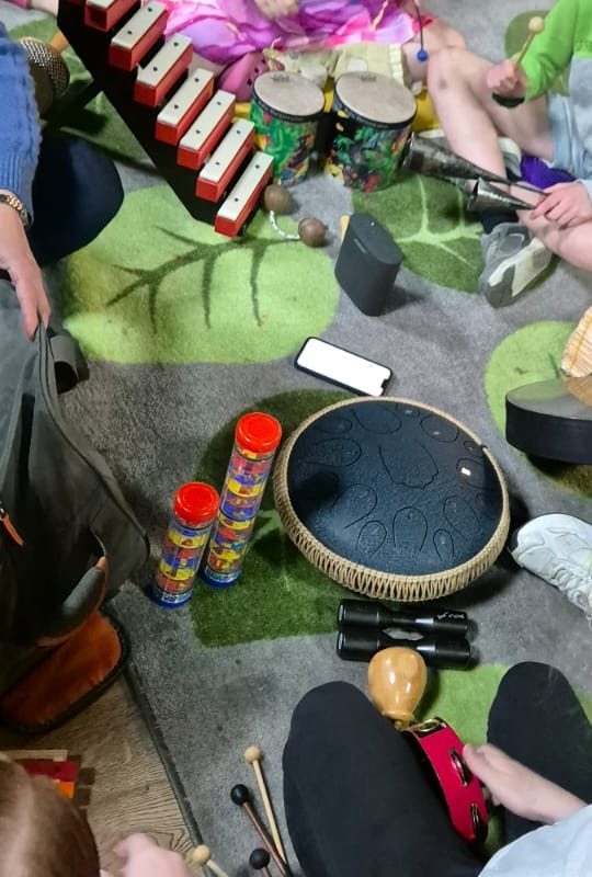 Drums, a xylophone, shakers and a tongue drum on a play mat during a music session