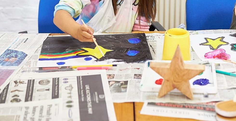 A hand painting a yellow star with a rainbow tail at a YPEP art workshop
