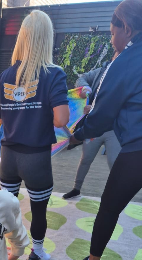 Two YPEP staff, one in a YPEP hoodie, seen from behind at an outdoor session